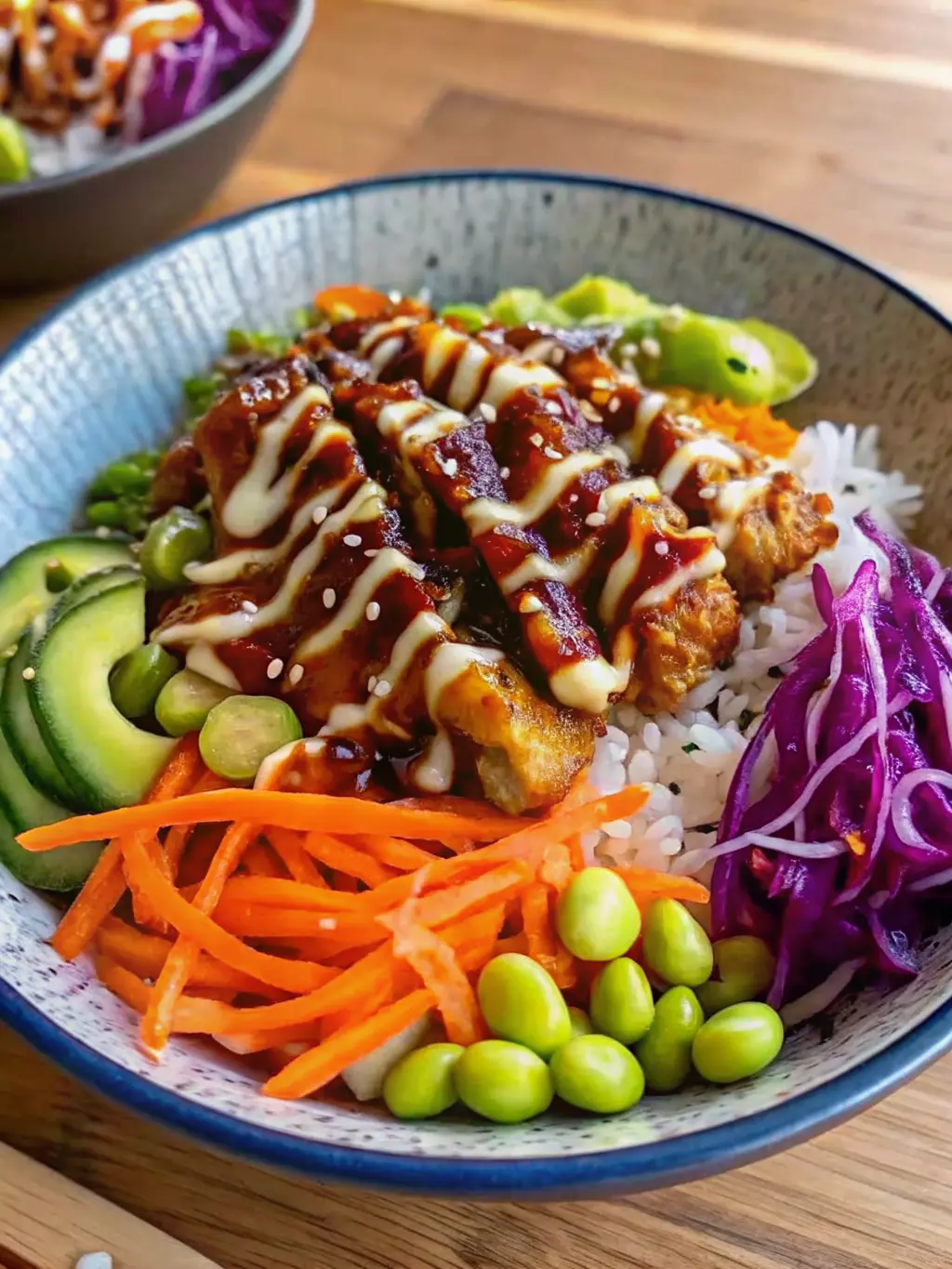 A beautifully composed close-up shot of the assembled Teriyaki Chicken Bowl, focusing on the texture and colors. The glistening teriyaki chicken, drizzled with a creamy white sauce and sesame seeds, sits atop fluffy white rice. Vibrant, crisp shredded carrots, bright green edamame, deep purple shredded cabbage, and refreshing cucumber slices are clearly visible. The blue ceramic bowl is on a light marble countertop, bathed in natural morning light, with soft shadows enhancing the depth. The presentation is clean and inviting. (3:4 ratio).