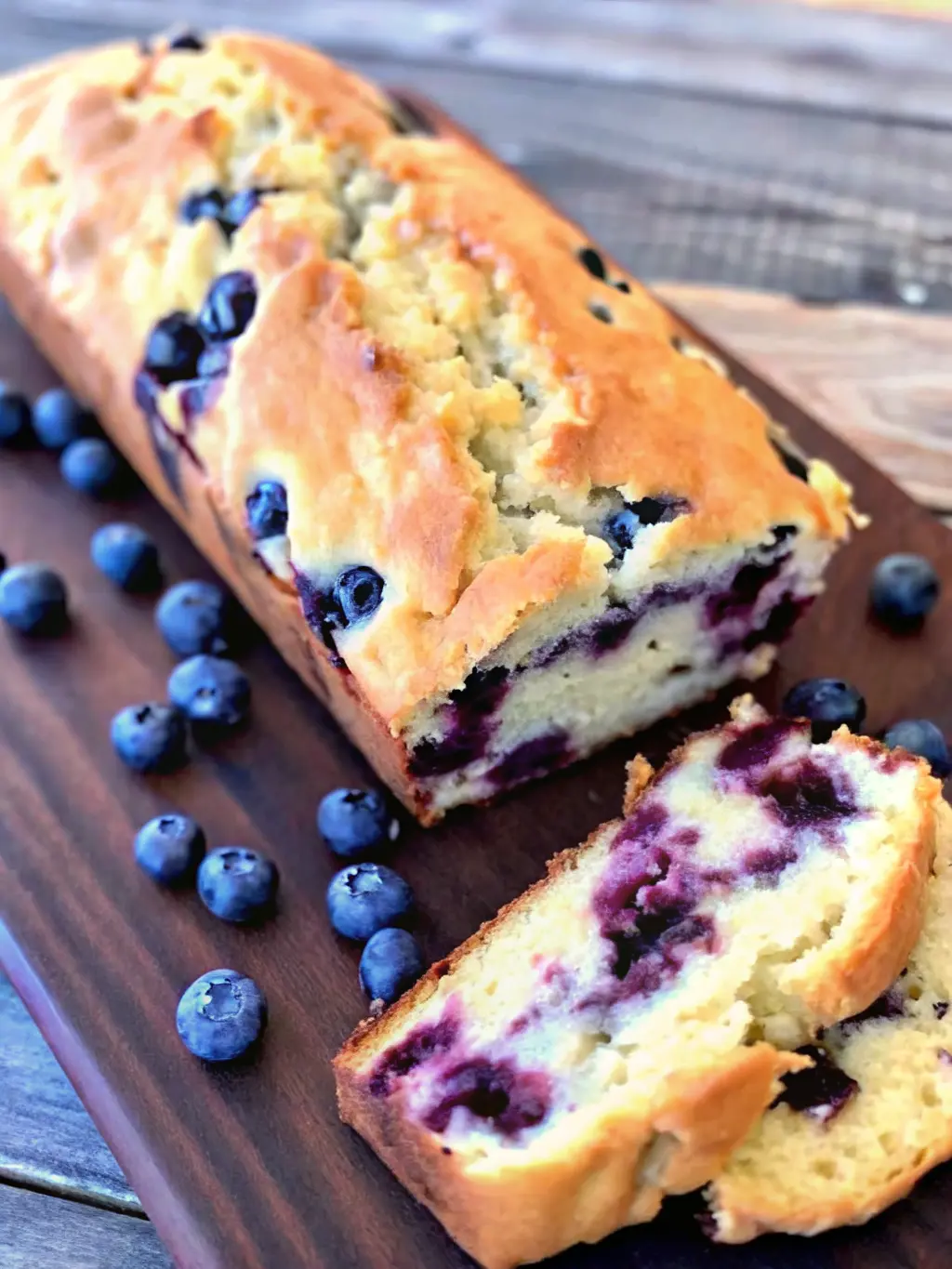 An overhead shot of fresh blueberries, softened cream cheese, flour, granulated sugar, and vanilla extract, neatly arranged in minimalist white ceramic bowls on a light marble countertop. Natural morning light creates soft shadows. A hint of fresh green herbs is visible in the background. Clean and tidy. No hands or people. (3:4 ratio)
