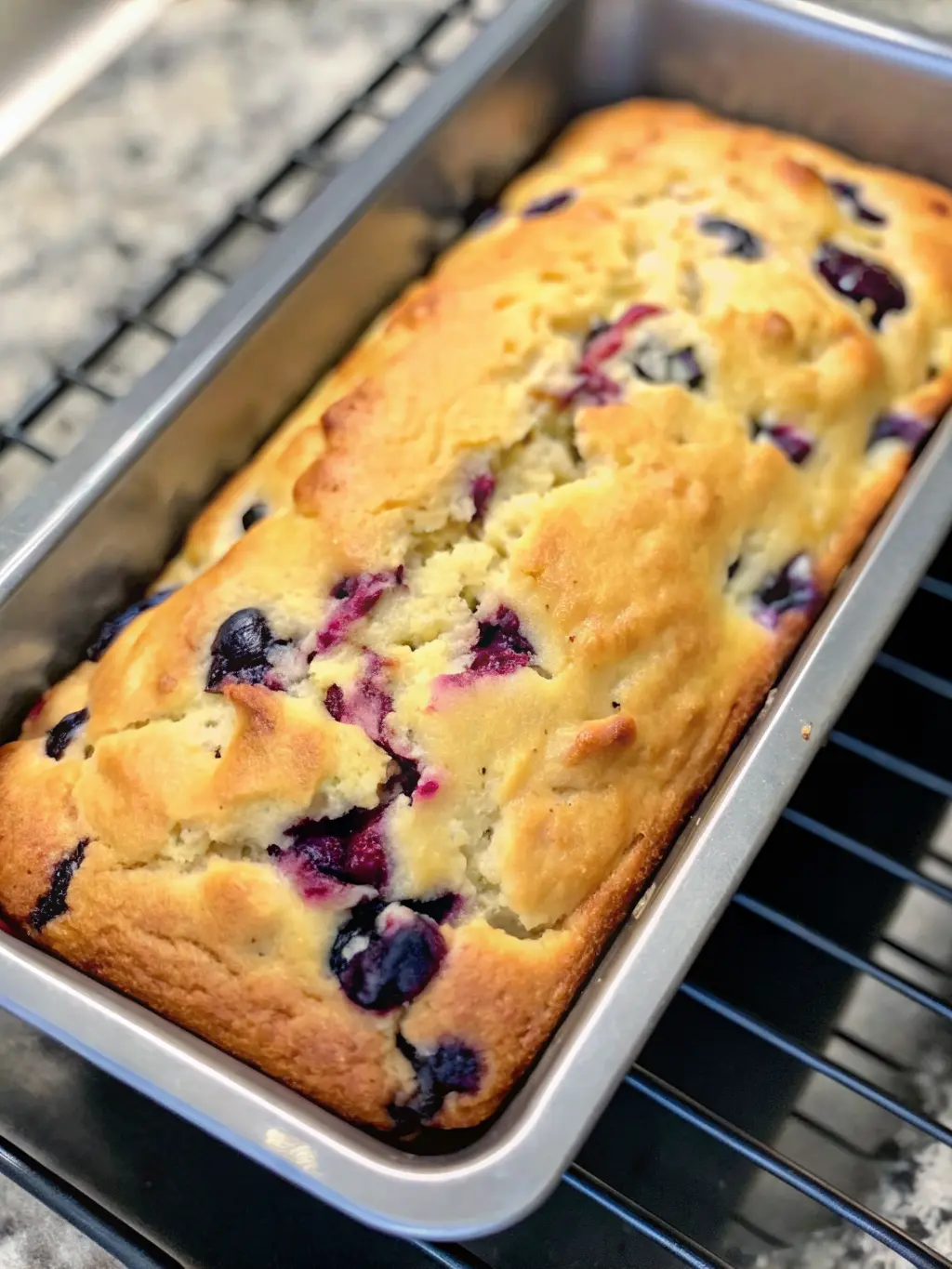 A partially mixed batter for Blueberry Cream Cheese Loaf in a large ceramic mixing bowl on a marble countertop. A creamy, swirled cream cheese mixture is visible within the batter, showing early stages of incorporation. Unmixed fresh blueberries are waiting nearby in a small white ceramic bowl. Natural morning light, soft shadows, warm tones. Clean and tidy. No hands or people. (3:4 ratio)