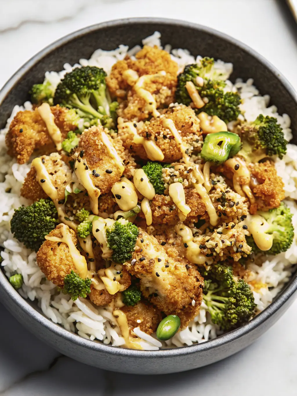 A captivating 3:4 shot of golden, crispy chicken pieces, just removed from a pan, resting on a wooden cutting board on a pristine marble countertop, ready to be added to the rice bowls. The chicken is visibly crunchy and perfectly browned, with subtle flecks of herbs. Natural morning light from an east window bathes the scene, creating inviting soft shadows and warm tones. Fresh green herbs are visible in the background, out of focus. No hands or people visible.