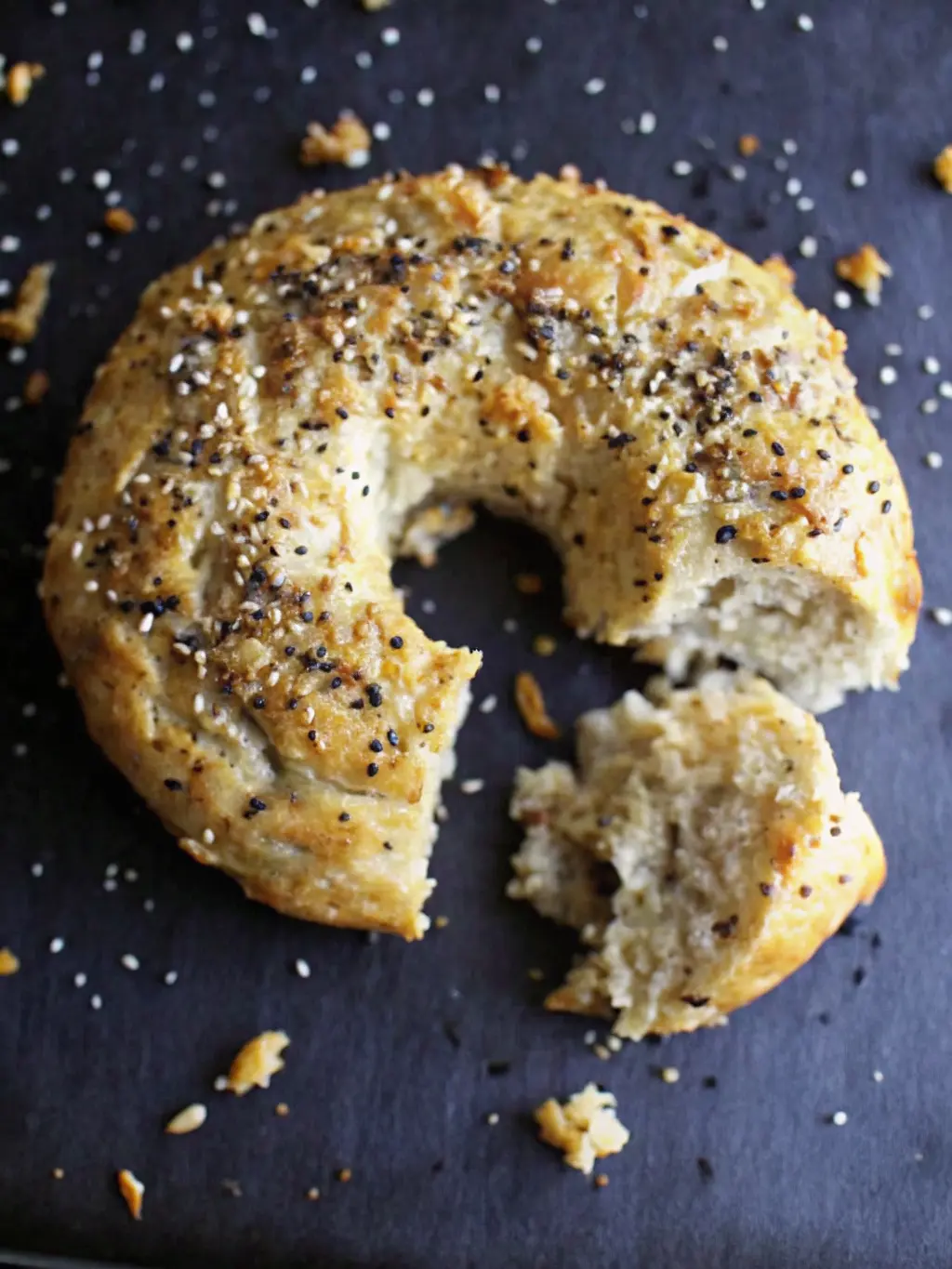 A minimalist flat lay of the key ingredients for Greek yogurt bagels: a bowl of self-rising flour, a container of plain Greek yogurt, and a small bowl of poppy seeds mixed with small, light-colored seeds, a whisked egg in a small white ceramic bowl, all arranged on a wooden cutting board on a marble countertop. Natural morning light creates soft shadows, fresh herbs in background. NO HANDS OR PEOPLE. (3:4 ratio)