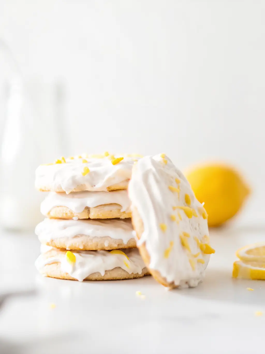 A bowl of fresh lemons and a zester on a wooden cutting board, next to bowls containing gluten-free flour, almond flour, and granulated sugar, arranged on a white marble countertop with natural morning light. Soft shadows, warm tones, clean and tidy presentation. Fresh herbs subtly blurred in background. NO HANDS OR PEOPLE. (3:4 ratio)