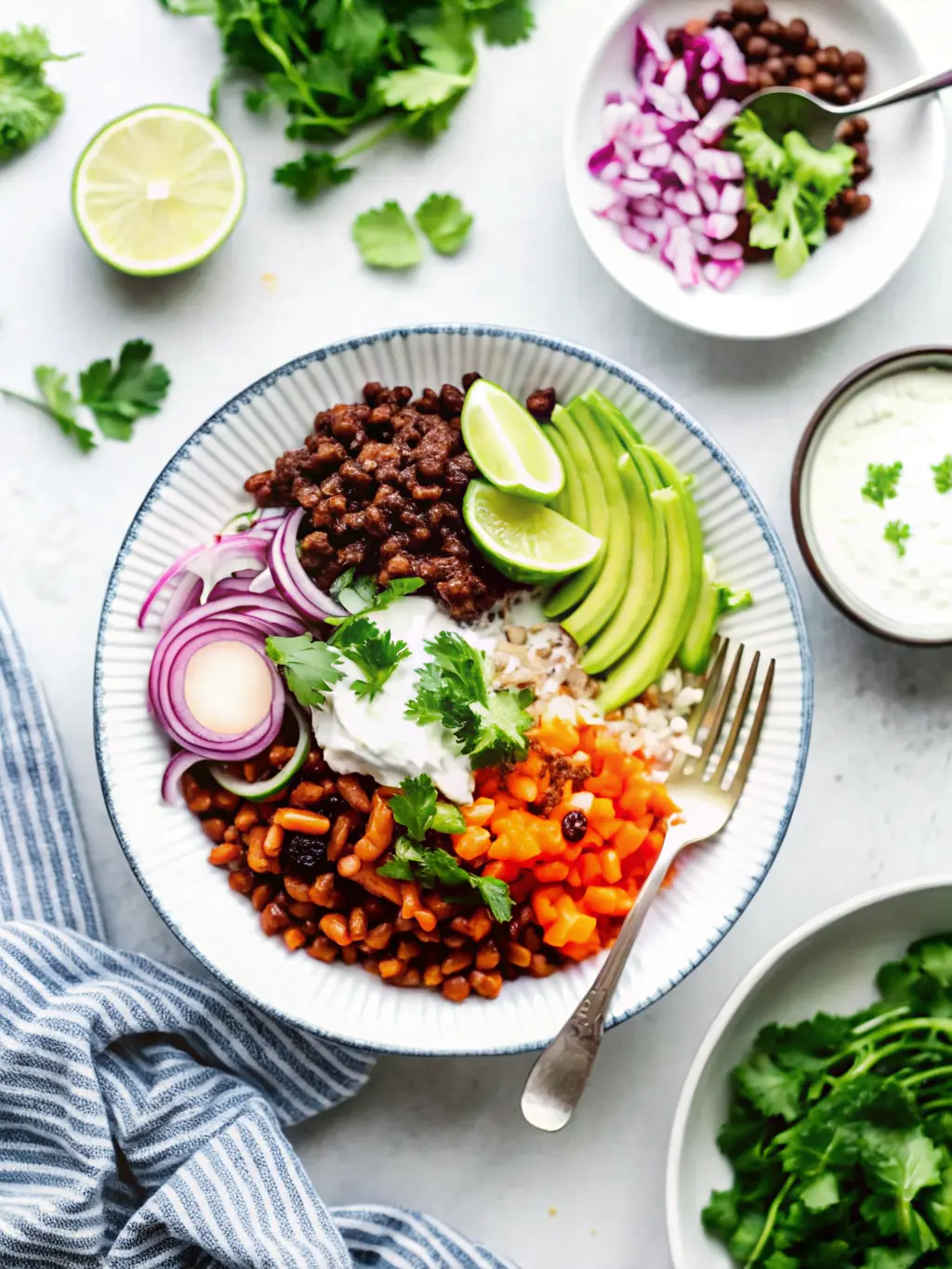 Process shot (3:4) showing seasoned ground beef sizzling in a stainless steel skillet on a stovetop (or on a marble countertop if stovetop view is not brand-compliant). The beef is reddish-brown and crumbly, with spices visible. Roasted sweet potatoes are visible on a baking sheet in the background, out of focus. Natural morning light, warm tones. No hands or people.
