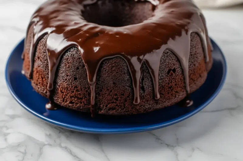 A dramatically styled dark chocolate bundt cake, the 'Mount Doom Cake', on a minimalist white plate. Rich, glossy chocolate ganache drips luxuriantly down the cake's dark, porous sides. The scene is set on a light marble countertop with subtle wood accents, bathed in natural morning light from an east window. Soft shadows enhance the cake's texture. A sprig of fresh herbs or subtle wood cutting board visible in the soft-focus background, no hands or people. (4:3 aspect ratio)